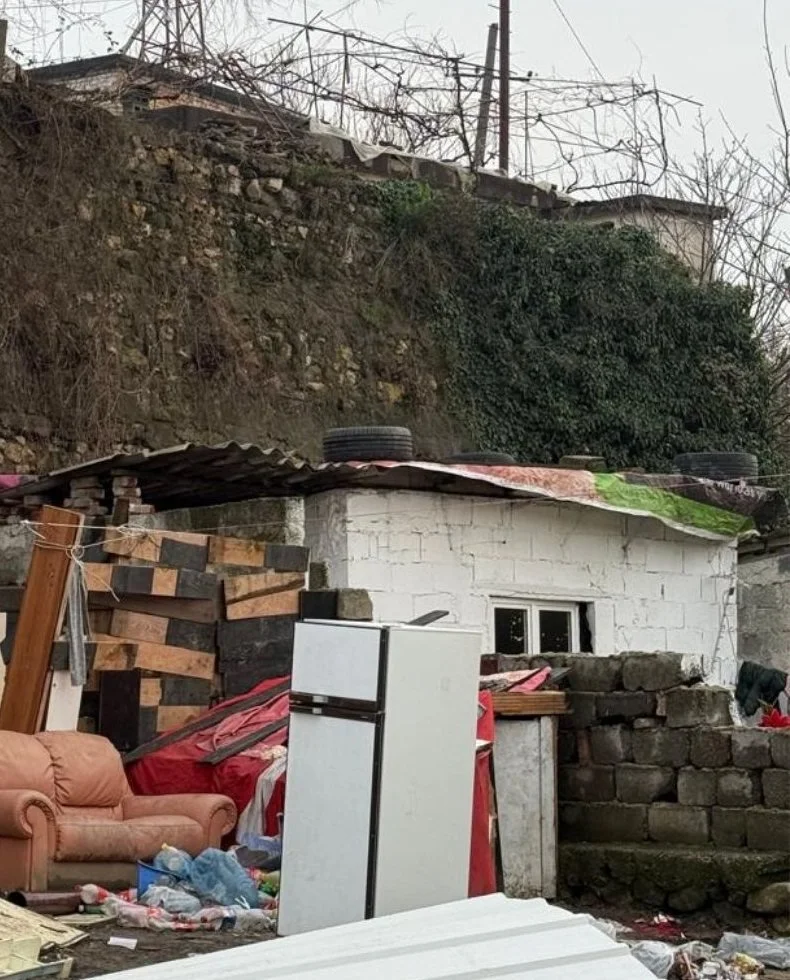 A flood-damaged home with ruined belongings piled outside