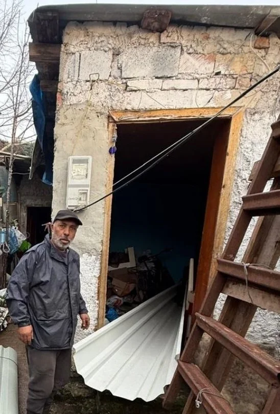 A man beside his home with new corrugated roofing panels