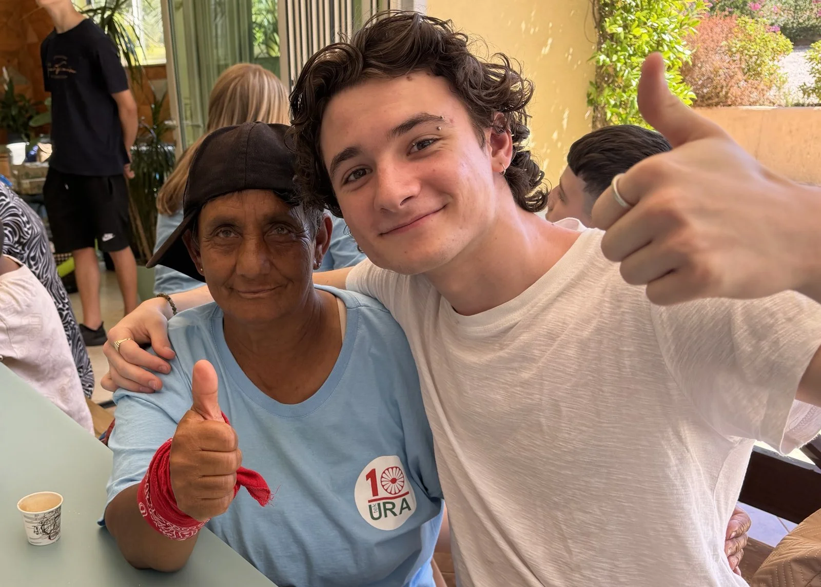 A young volunteer and a friend from the Albanian community, both giving a thumbs up at camp