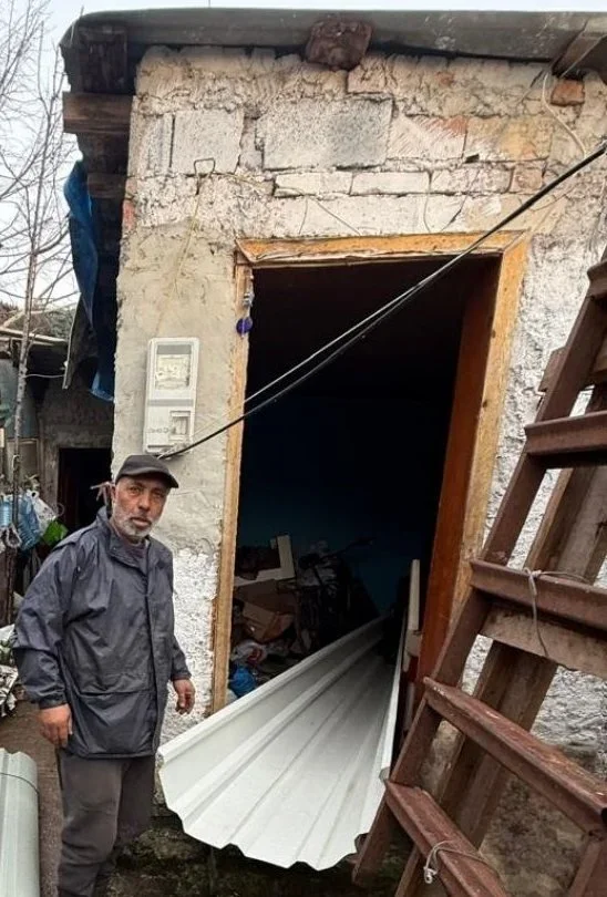 A man beside his home with new corrugated roofing panels