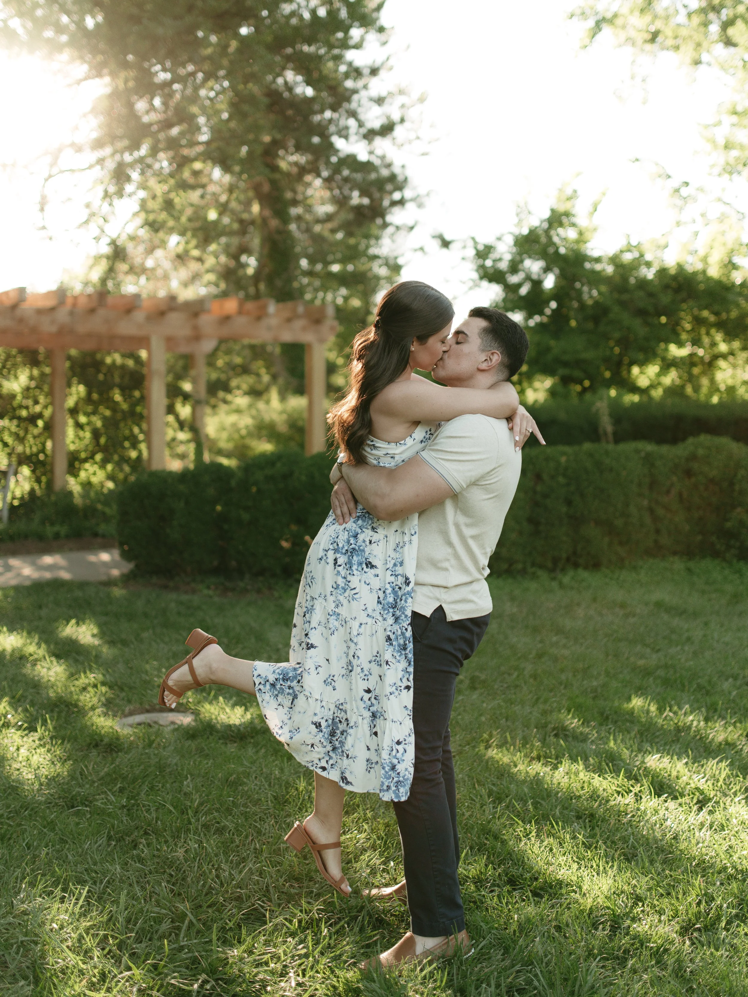 Ault Park Engagement Photoshoot. Guy holding up girl and kissing in a garden during sunset. Summer engagement photo.