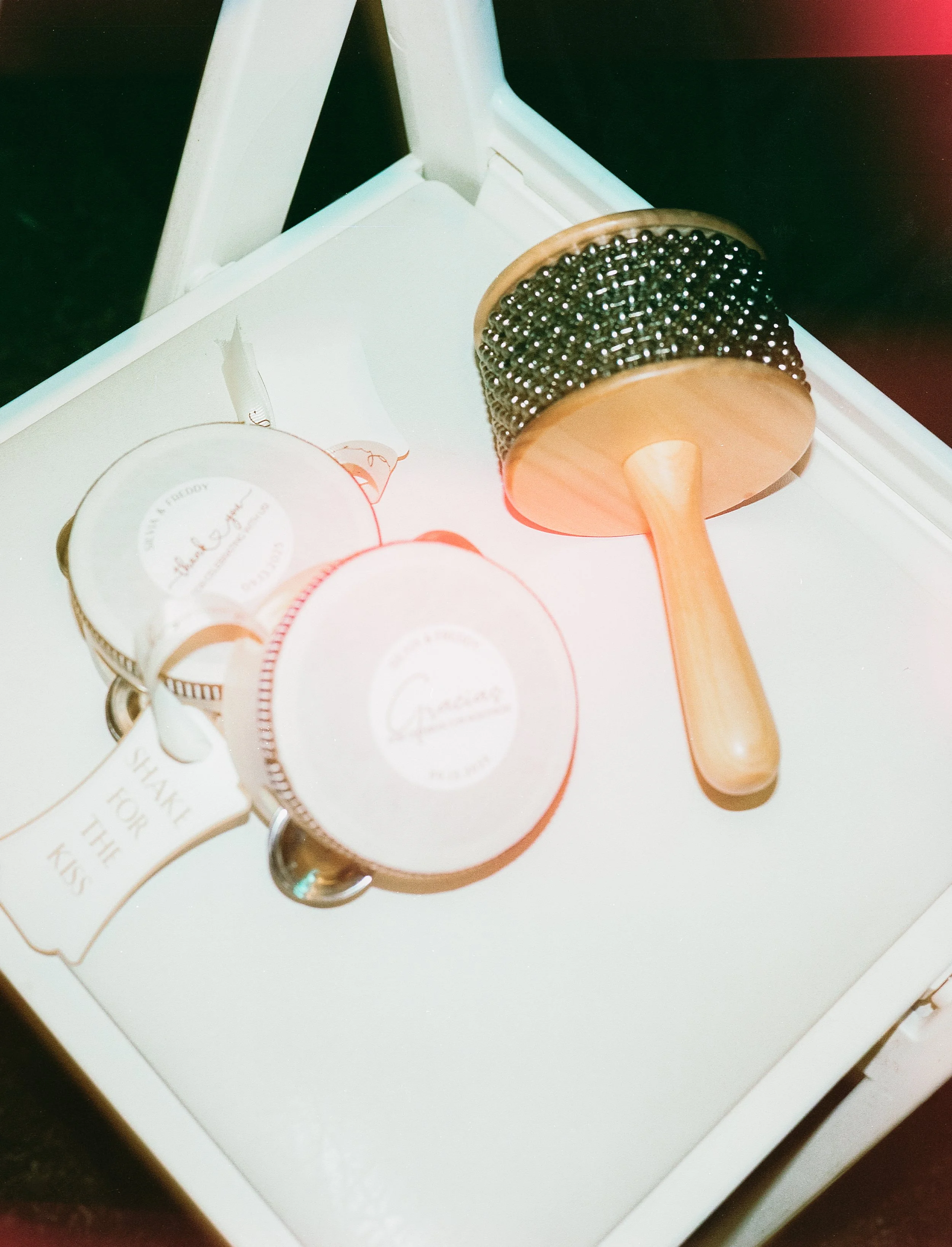 A white tray holding a wooden-handled massage roller with metal spikes, and three small jars of skincare products with white labels.