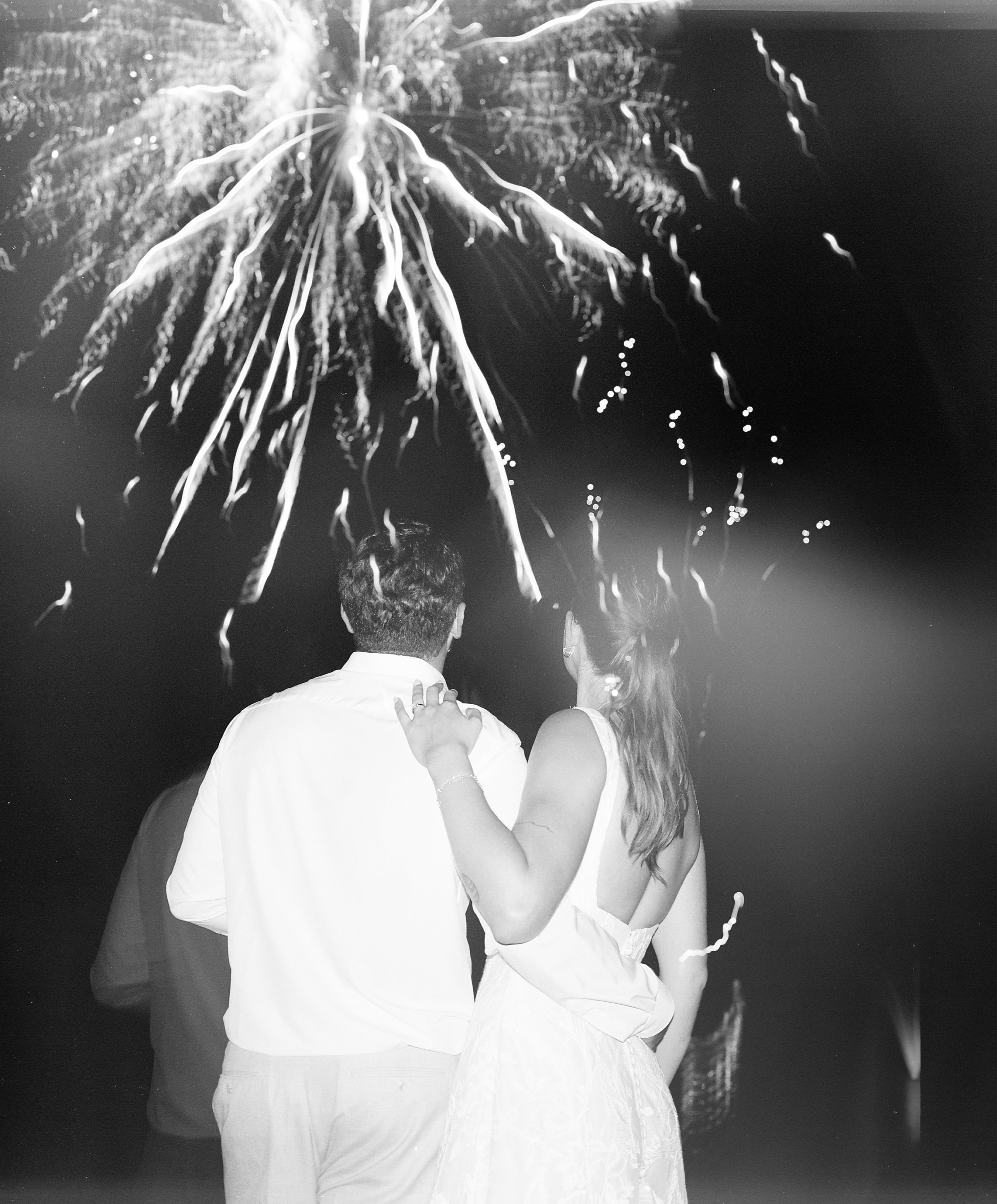 A couple at night watching fireworks display in the sky.
