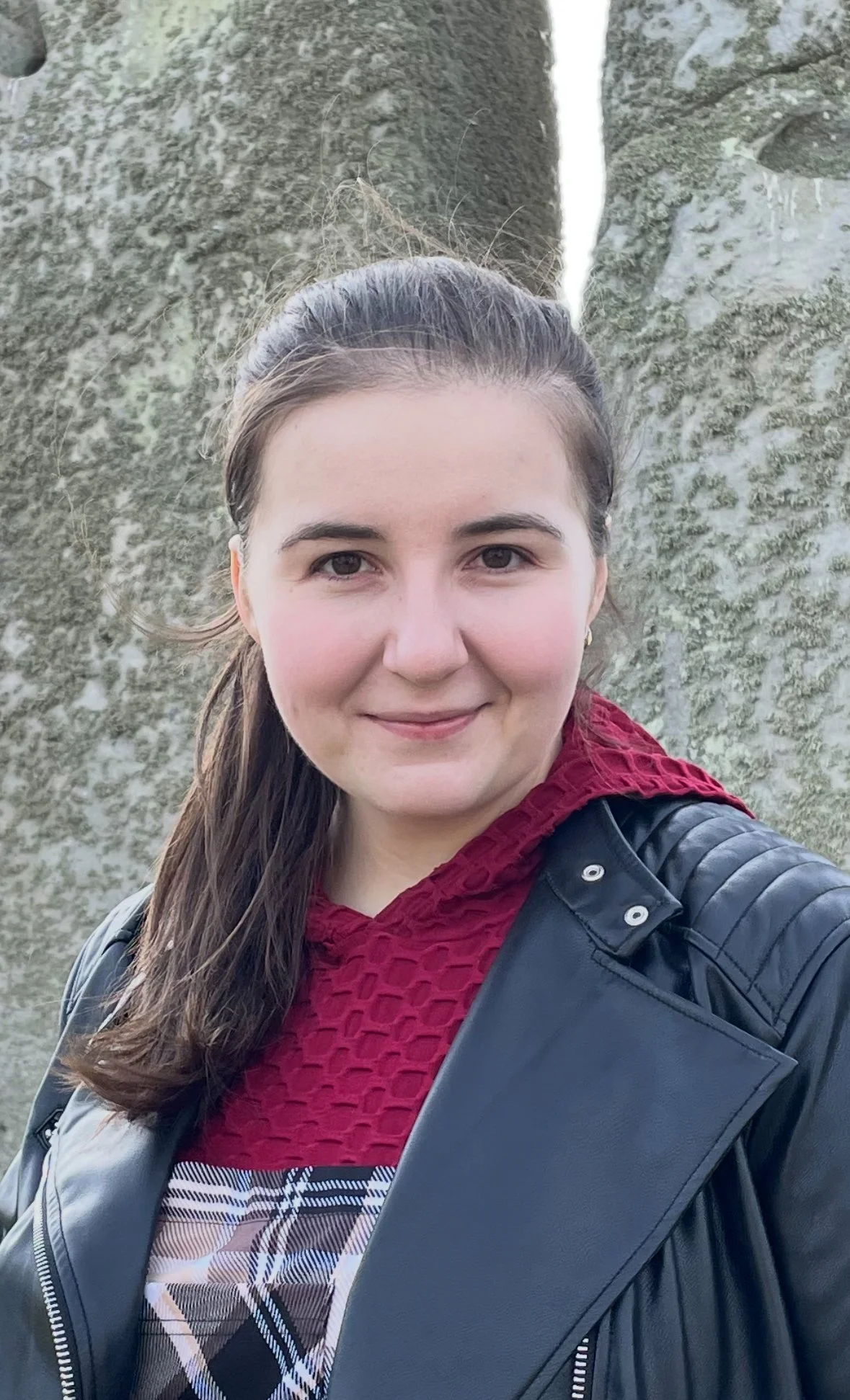 Close-up portrait of a smiling woman with dark skin and vibrant, curly orange hair, wearing a green top.