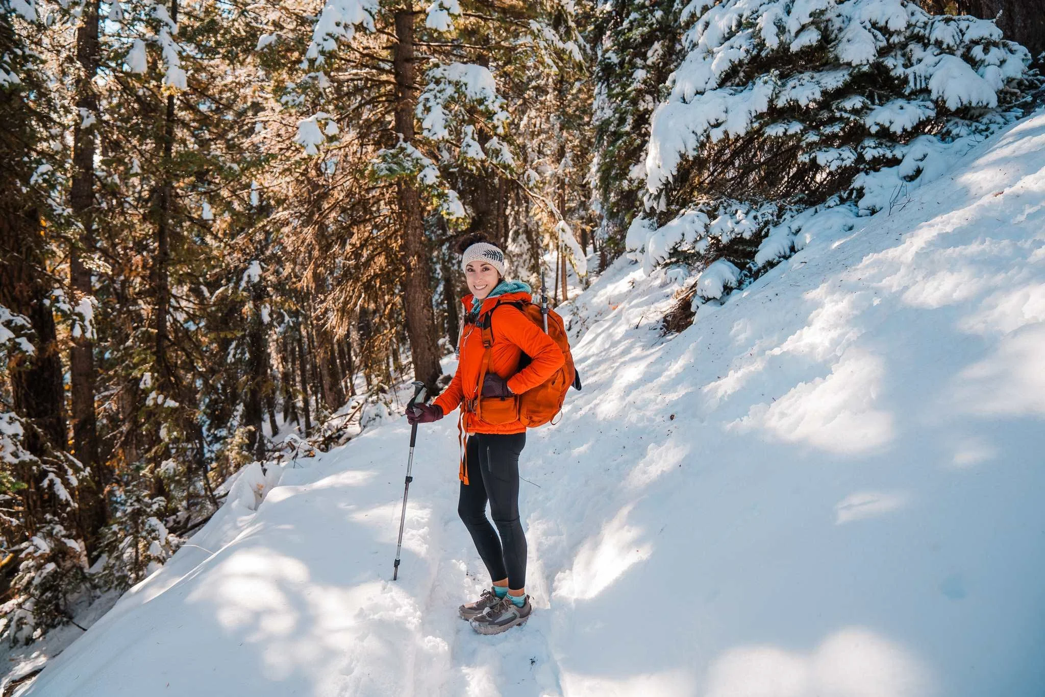 a woman hiking on a snowy trail, bundled up for cold weather