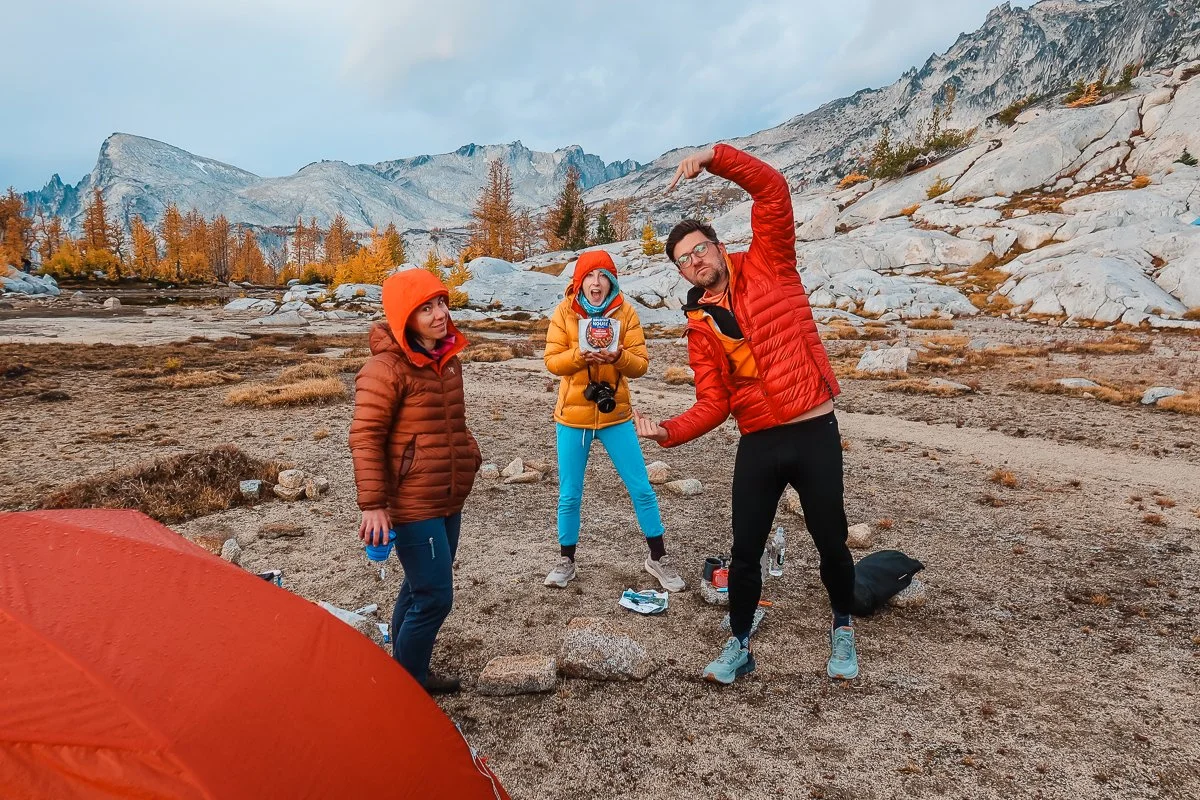 three backpackers at camp having breakfast in down jackets and fleece base layer bottoms in the core enchantments