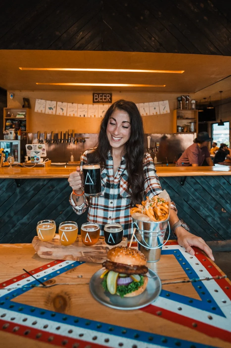 Girl enjoying beer and food from A-Frame Brewing Co and Flipside Burgers 