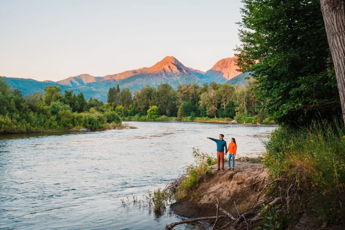 a couple standing near the shore of the Wenatchee River at sunrise