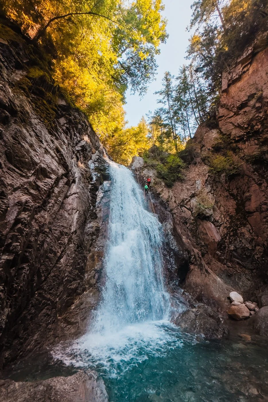 Man rappelling through a waterfall on West Coast Canyoning adventure