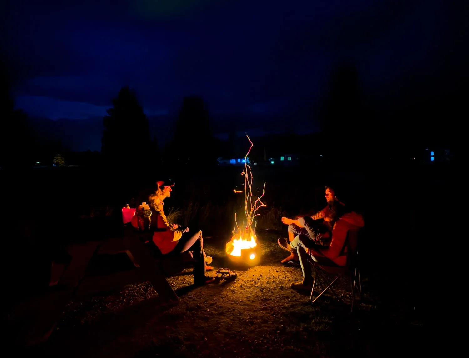 four people sitting around a campfire at night at whistlers campground in jasper national park