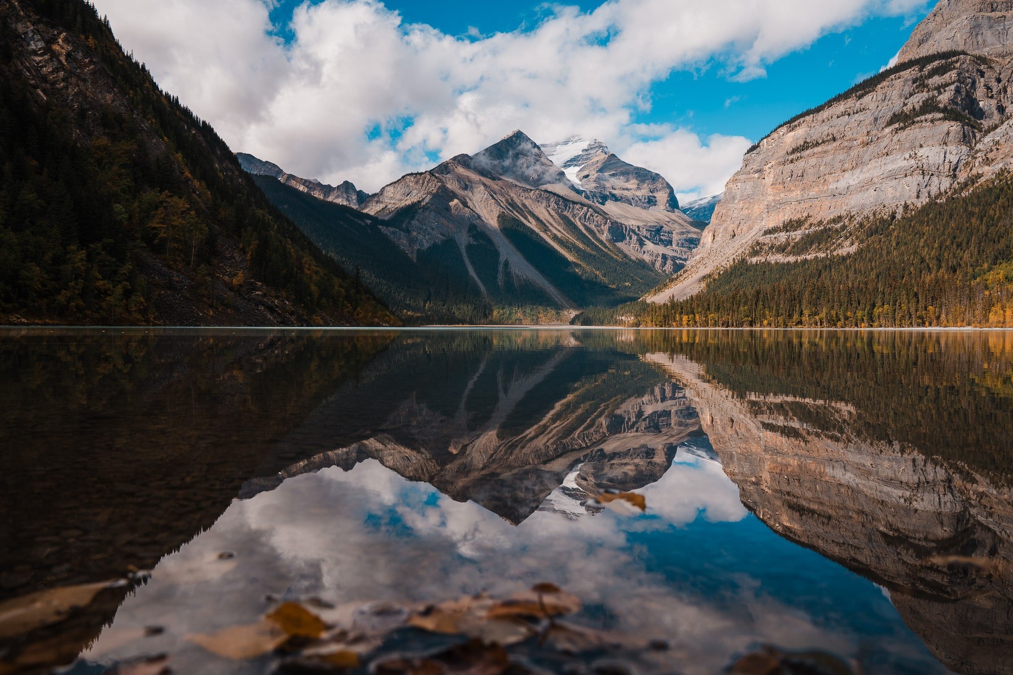 Mountains reflecting perfectly in a glassy lake along the berg lake trail in mount robson provincial park