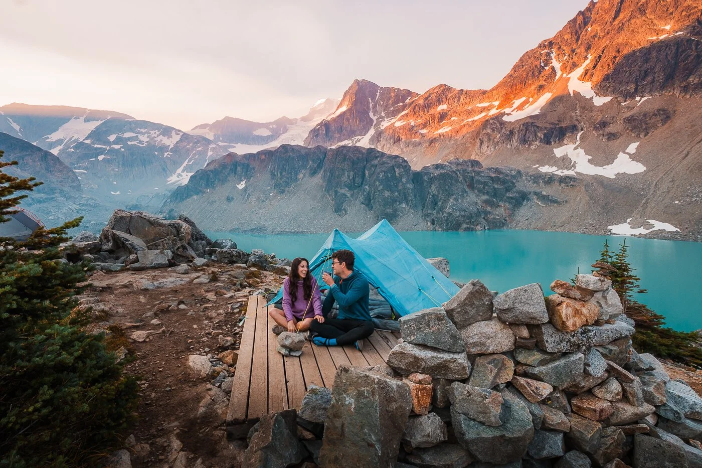 Couple sitting on a camping platform with backpacking tent overlooking Wedgemount Lake in Garibaldi Provincial Park