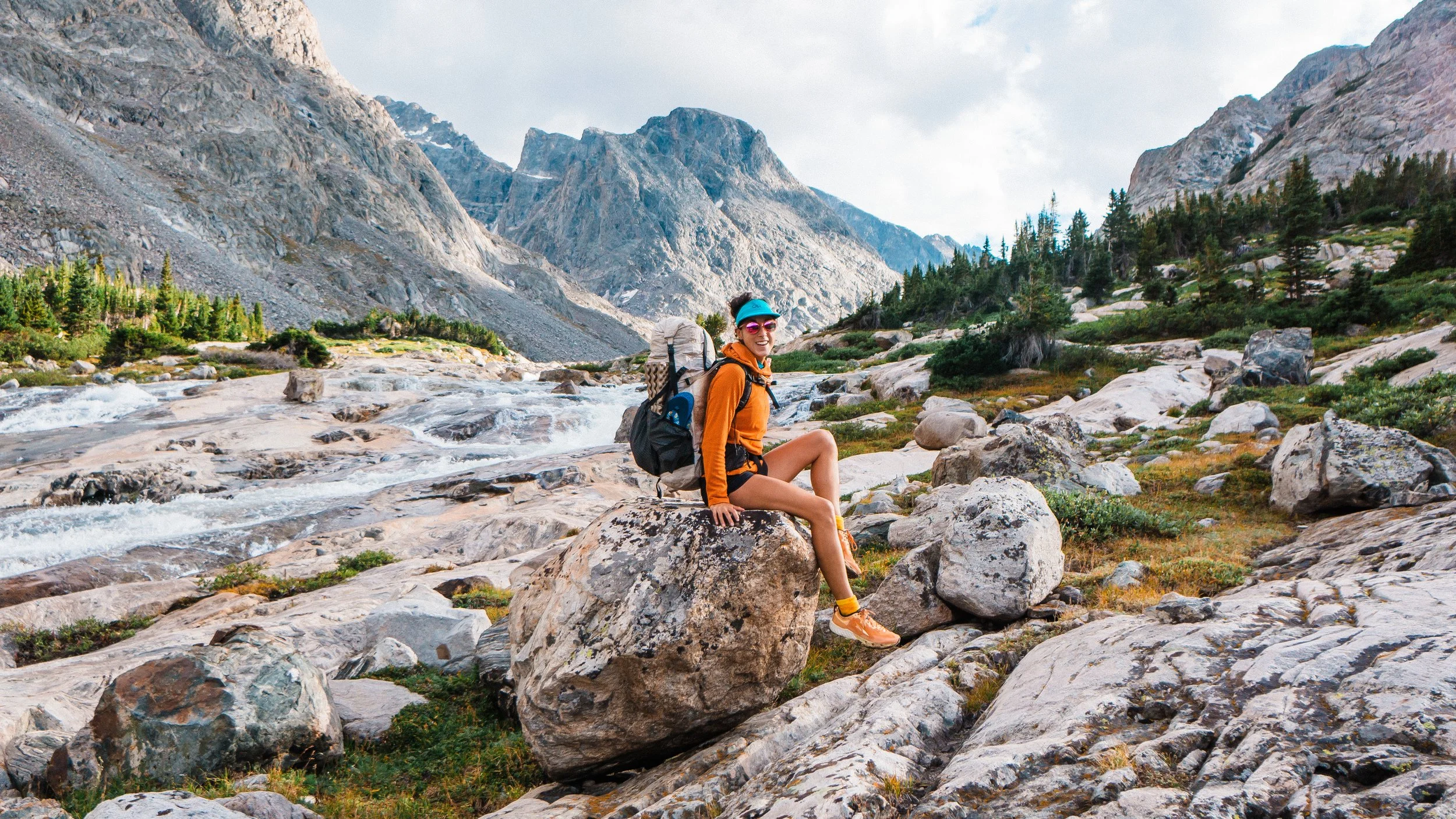backpacking girl sitting on a boulder in wind river range wyoming