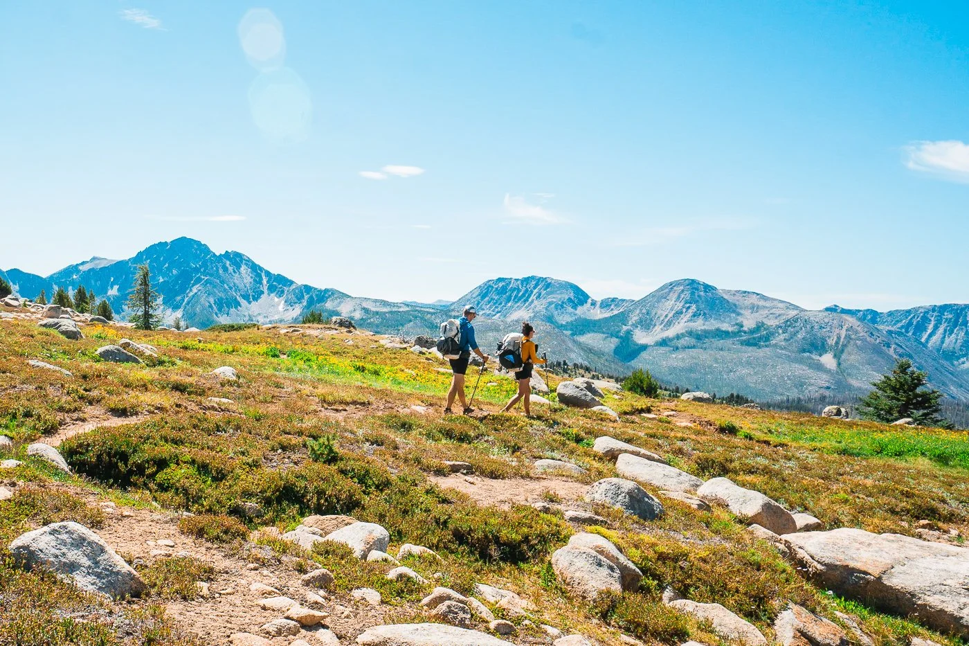 two backpackers hiking on a trail through the pasayten wilderness with mountains in the background