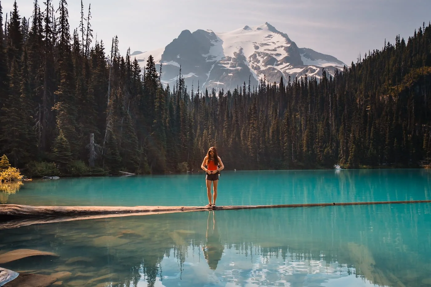 Hiker standing on floating log at middle Joffre Lake