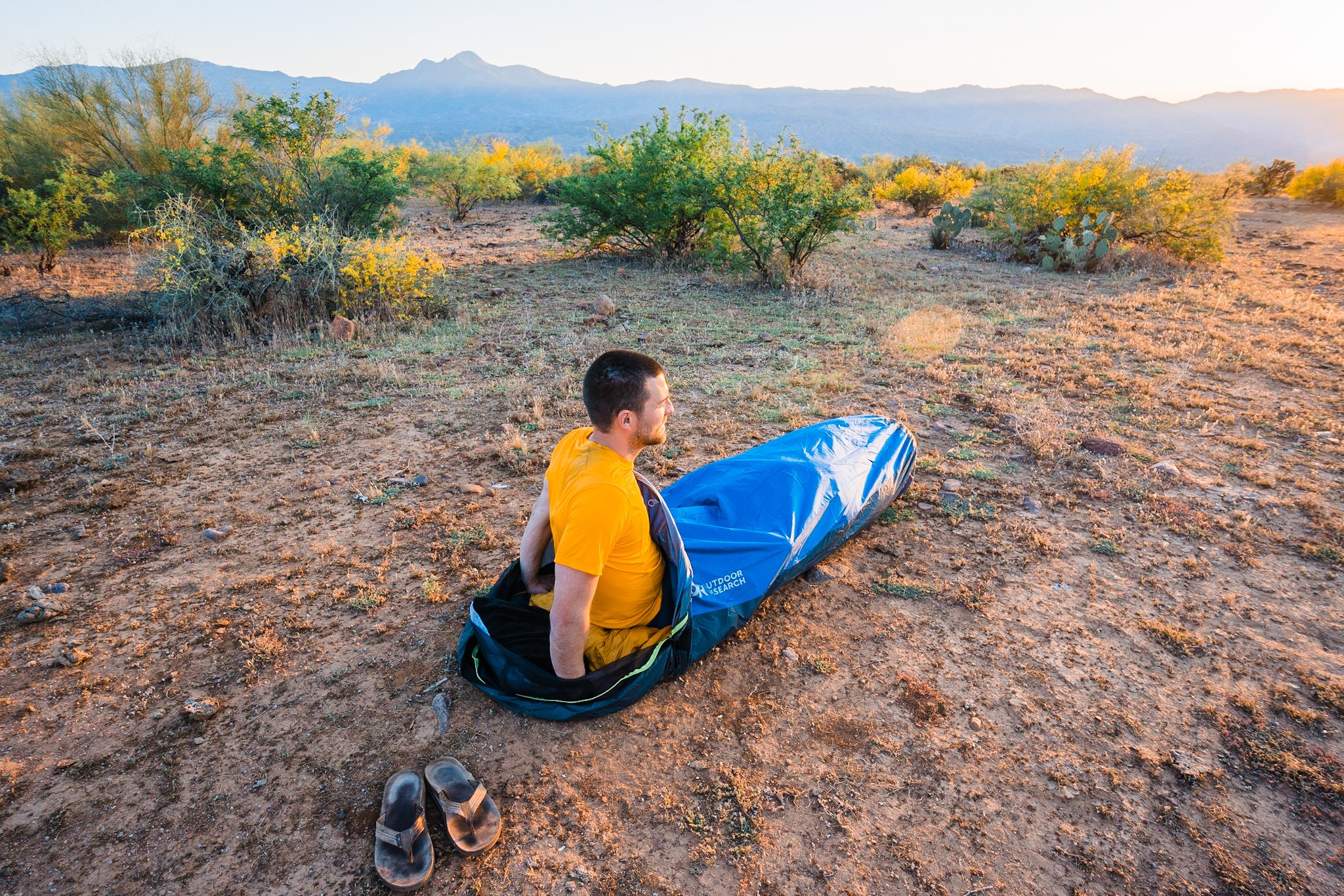 a man sitting in a bivy sack, camping in the desert