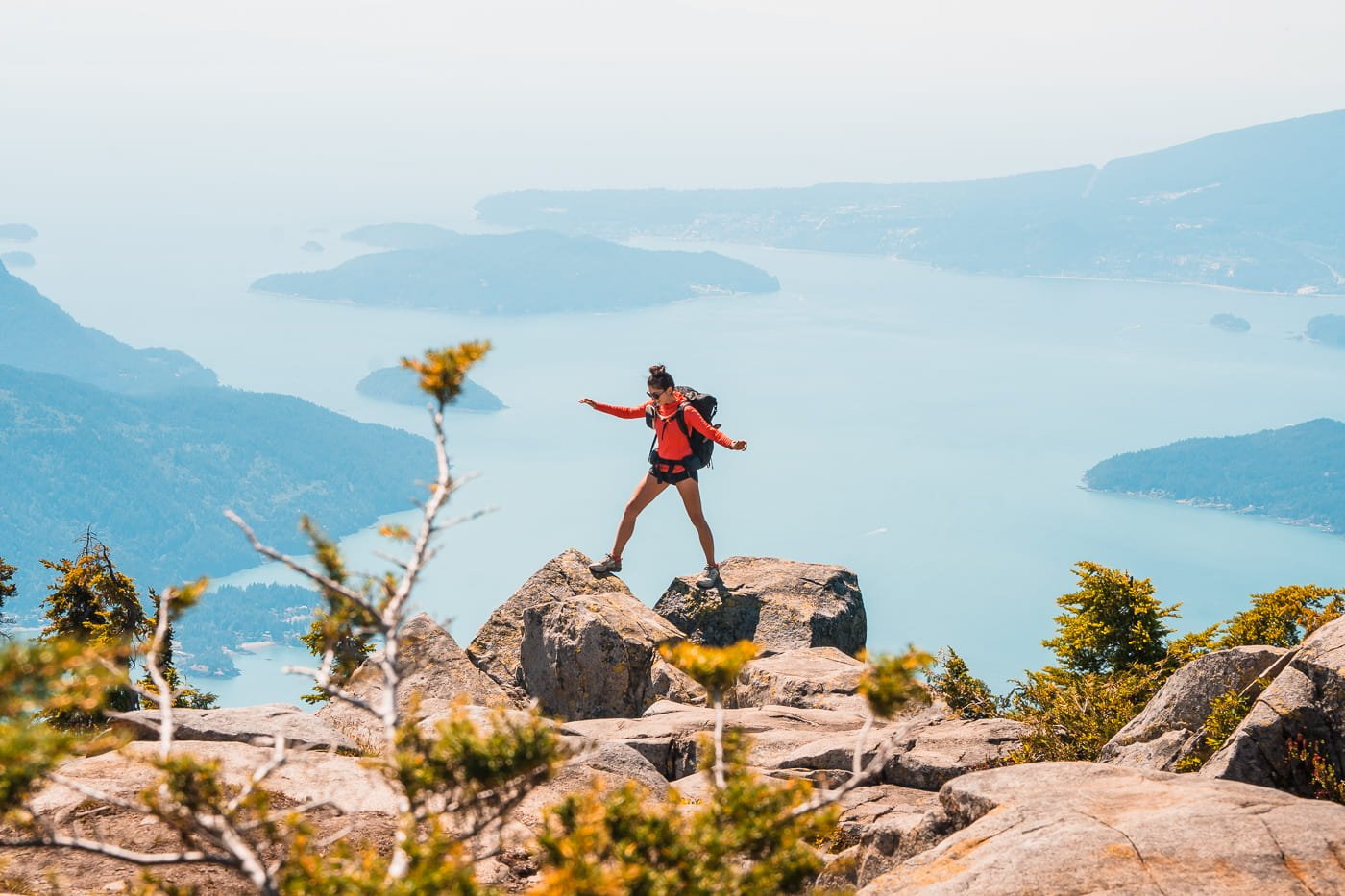 Girl walking along rock slabs overling the Howe Sound while backpacking the Howe Sound Crest Trail