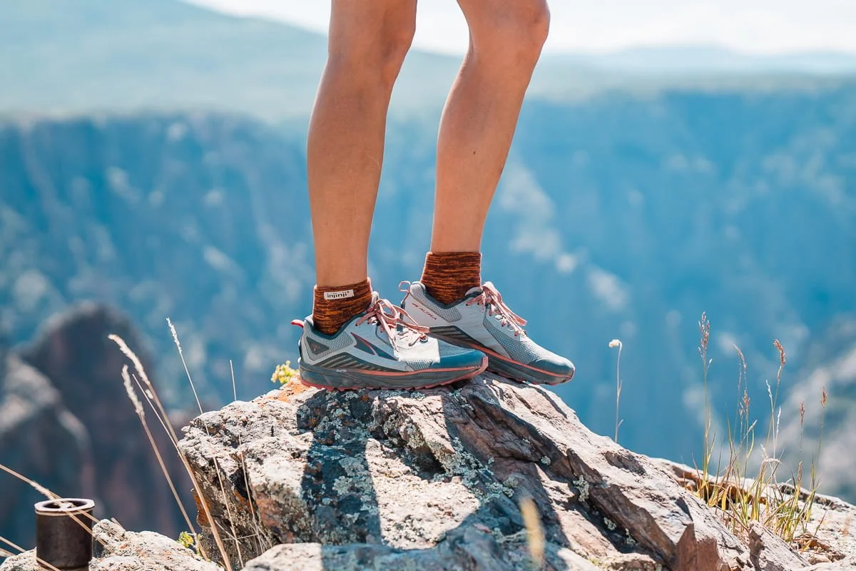 Standing on a rock, close up shot of Altra timp trail runners with injinji socks