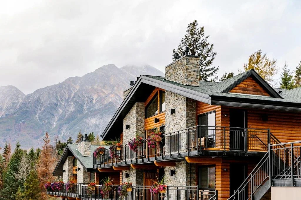 A beautiful wooden lodge with flowers on the balconies and mountains in the background at Pyramid Lake in Jasper