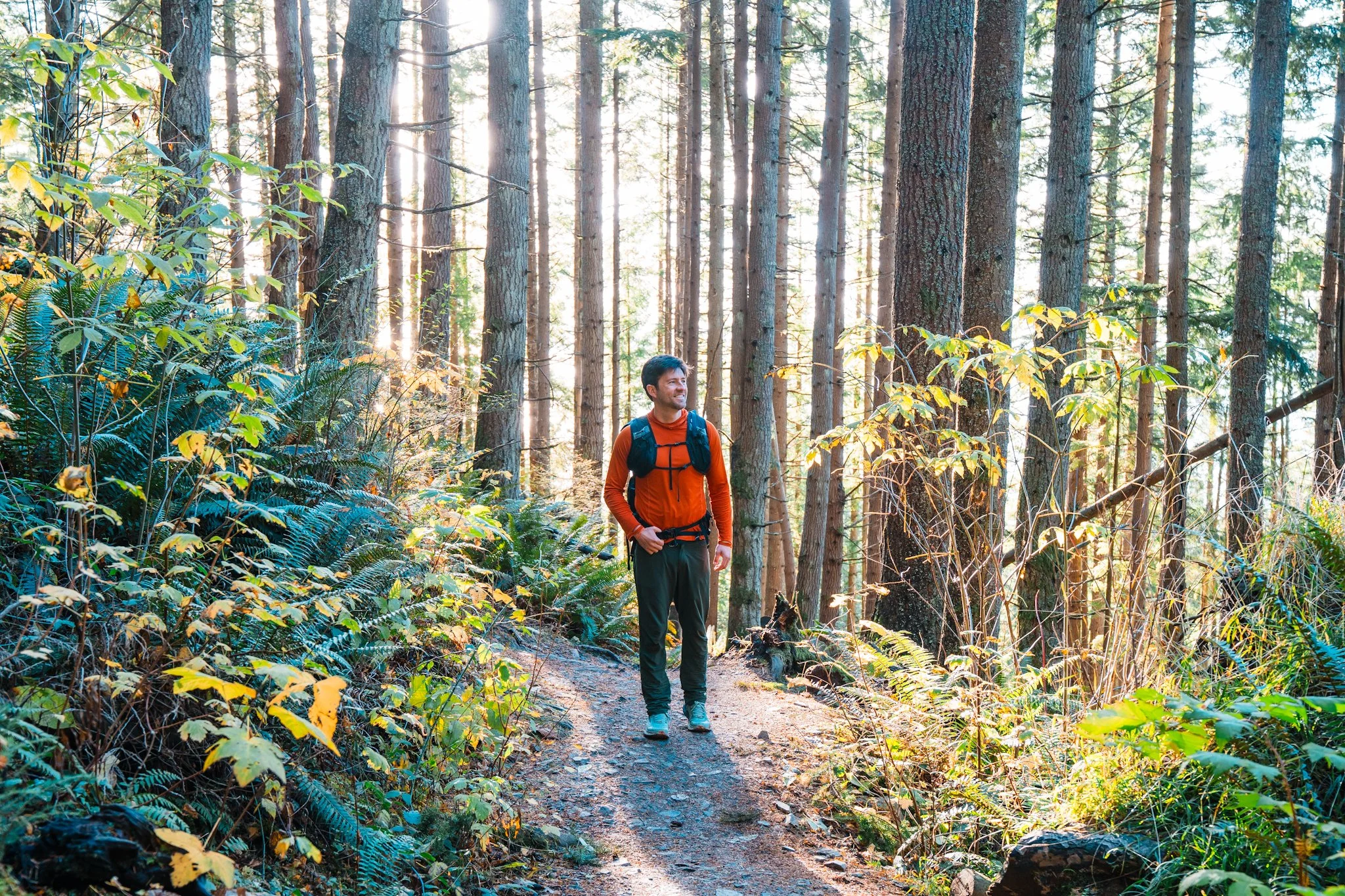 a man hiking through a forest in a long sleeve sun hoodie and hiking pants