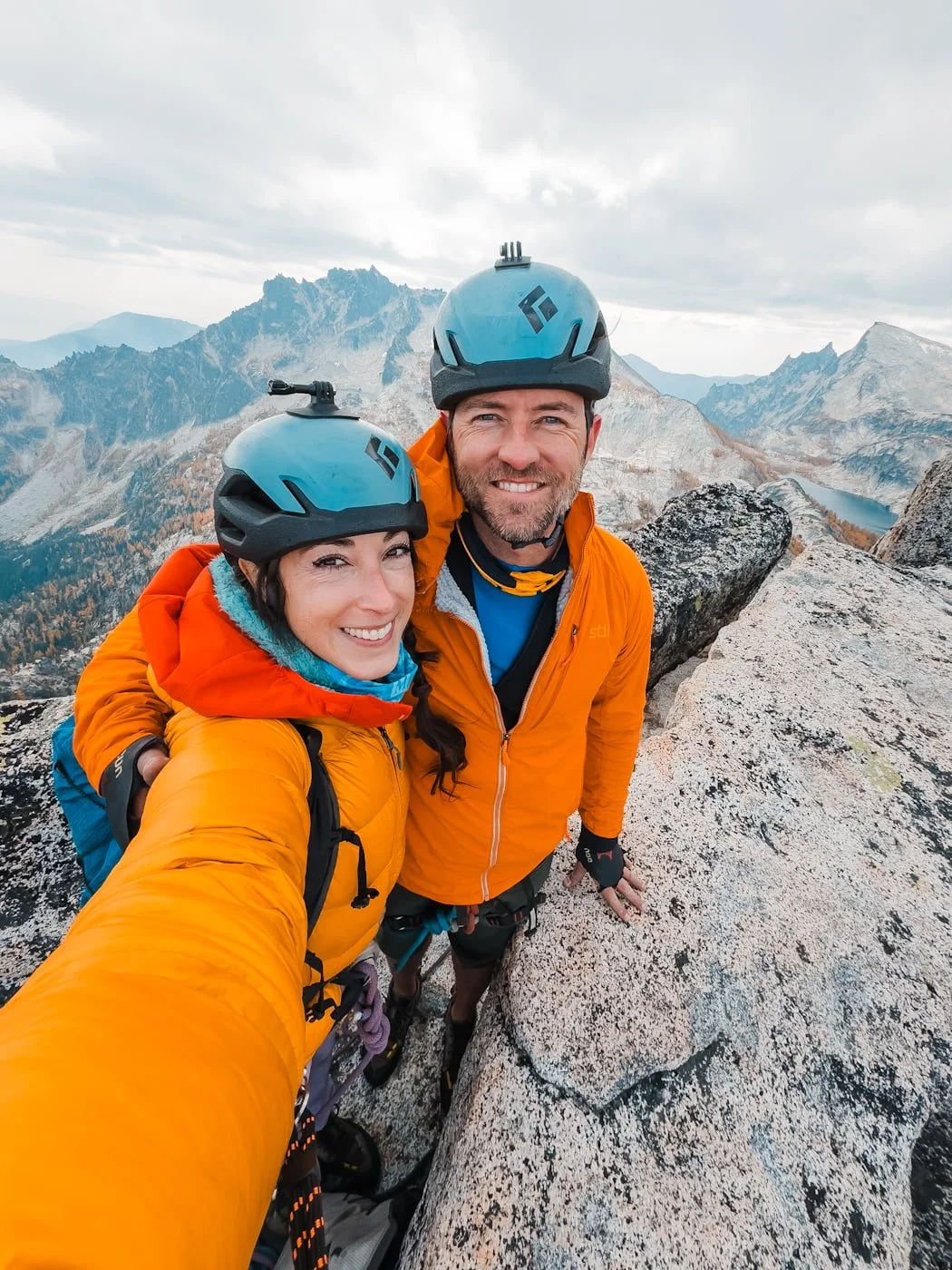a couple of climbers wearing helmets standing on the summit of prusik peak in the enchantments