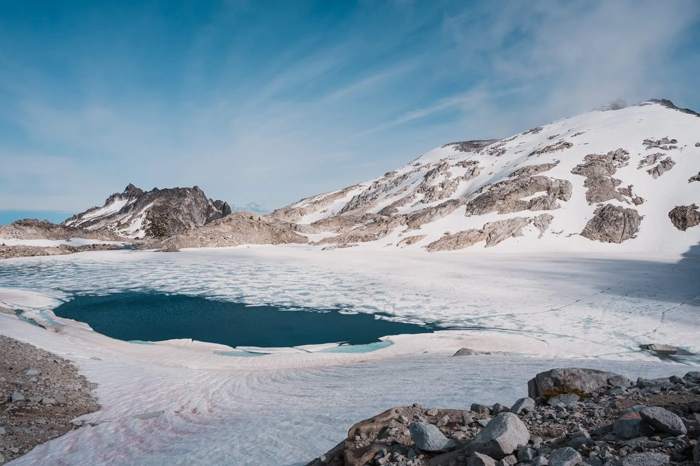 a snowy and melting lake with peaks in the background in the core enchantments