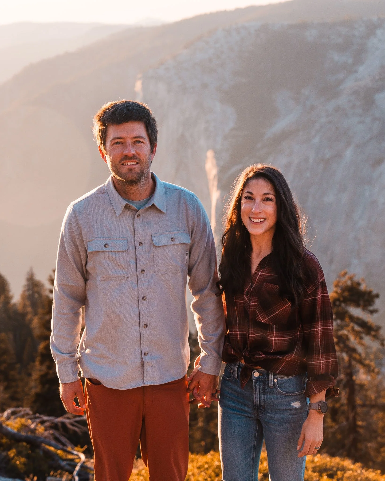 a couple smiling for the camera at sunset