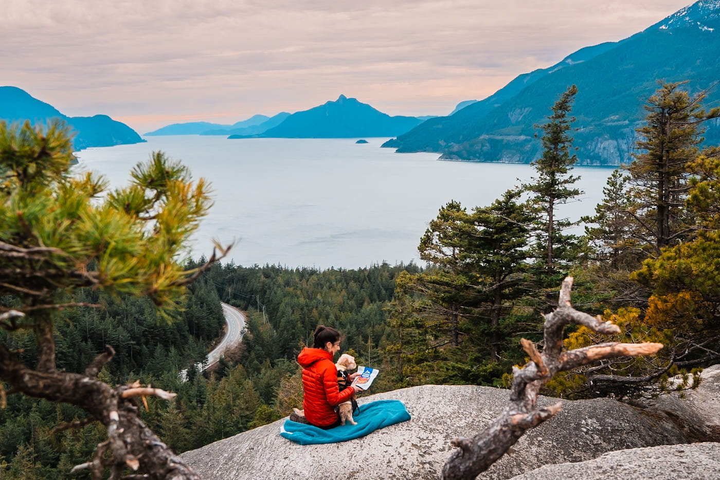 girl and dog sitting on a picnic blanket overlooking the Howe Sound from Quercus Point in Murrin Park