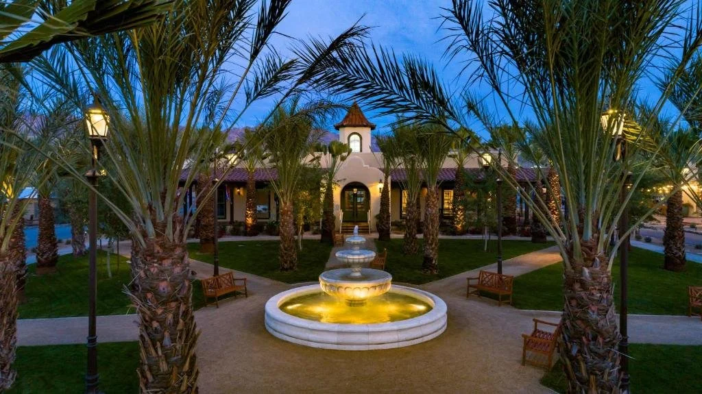 the inn at death valley, showing the entry area with a fountain and hotel and palm trees