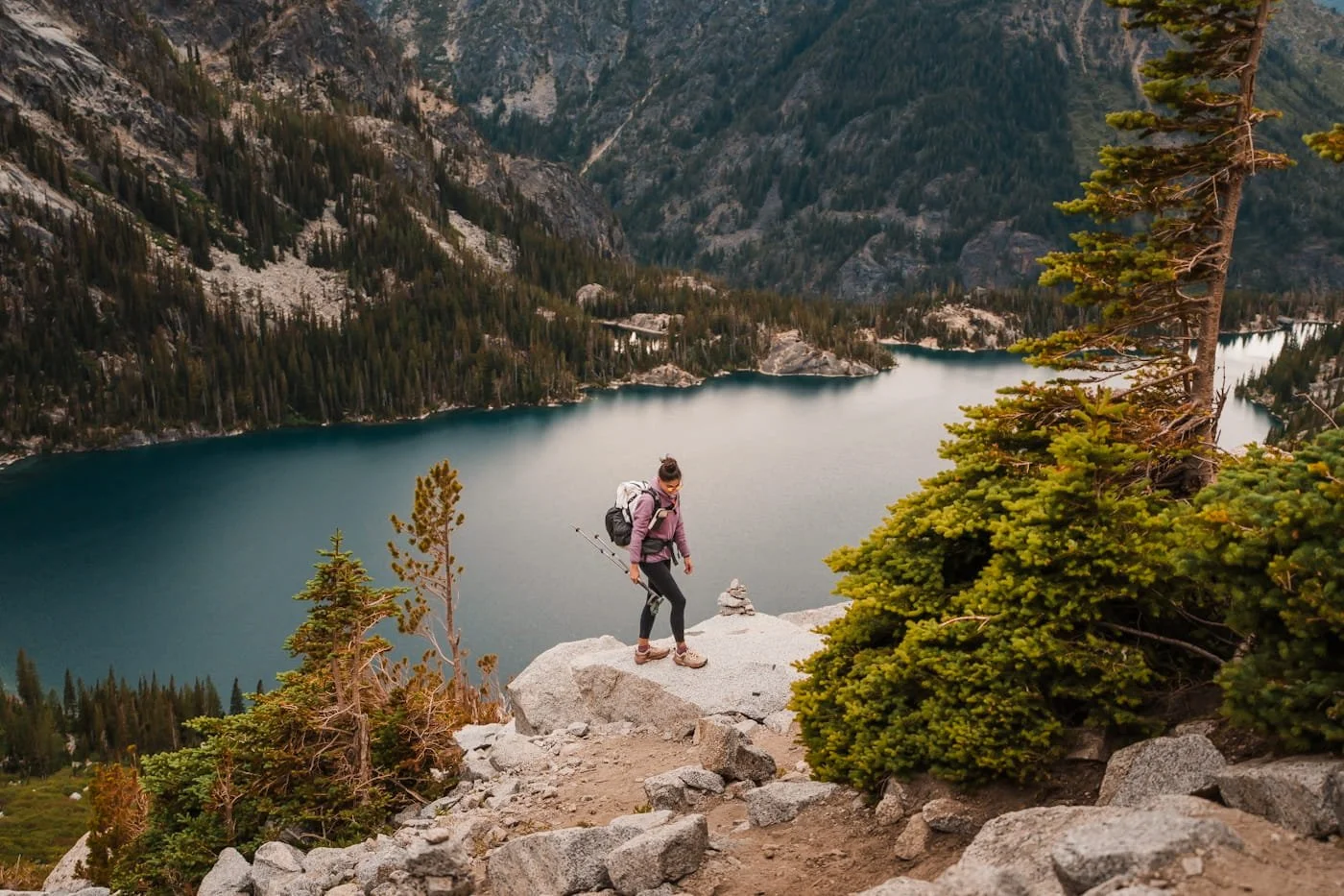a hiker walking on a rock, with a lake in the background while heading up aasgard pass in the enchantments