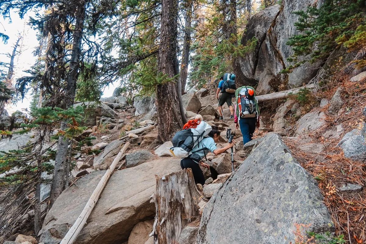 backbackers ascending a rocky section of the colchuck trail to colchuck lake