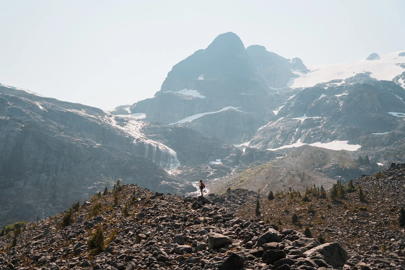 a hiker on a rocky ridge near Upper Joffre Lake with a huge peak in the background