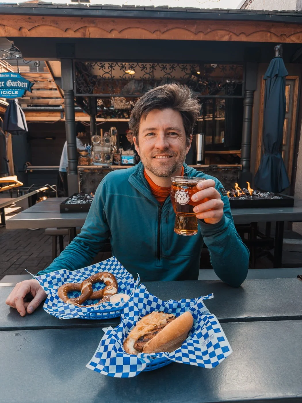 Guy eating bratwurst, soft pretzel and drinking amber beer