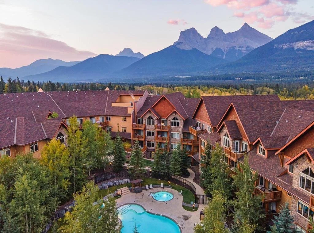 Looking down at the Stoneridge Mountain Resort and the pool in Canmore, with the three sisters mountains in the background