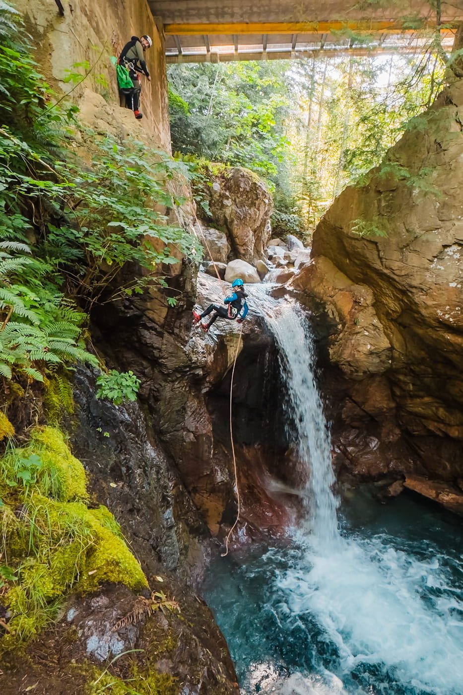 Man rappelling through a waterfall on West Coast Canyoning adventure