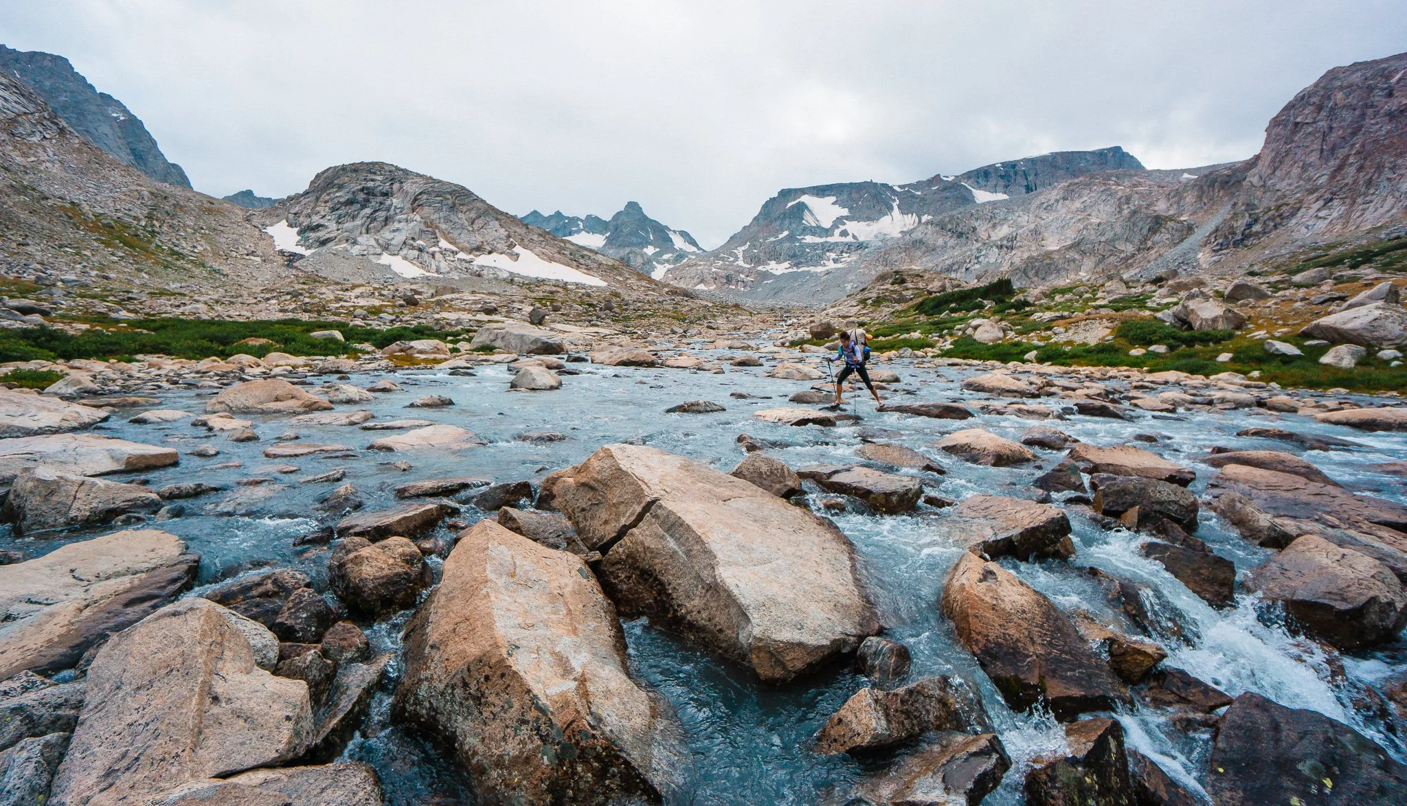girl backpacking and crossing a river in the wind river range wyoming
