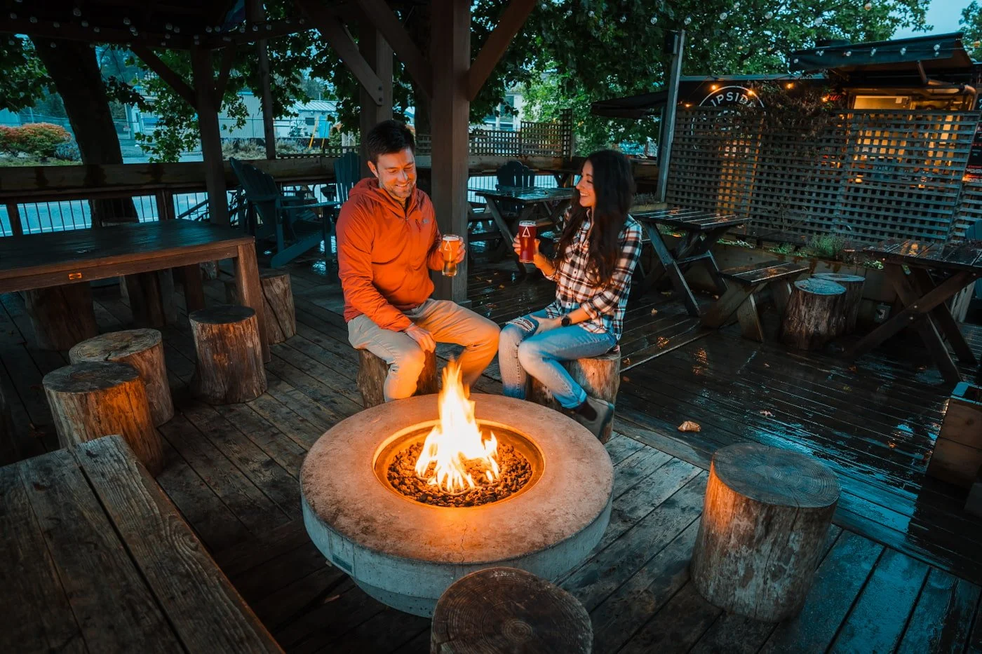 a couple enjoying evening fireside drinks at A-Frame Brewing Co