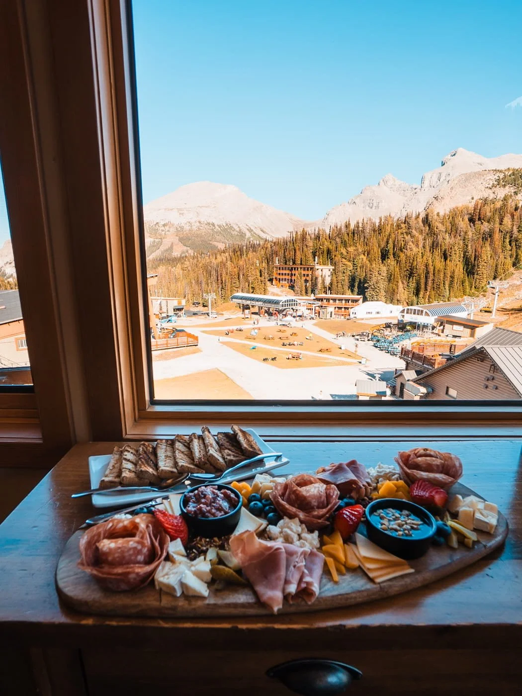 Window views from a room at the Sunshine Mountain Lodge with a charcuterie board