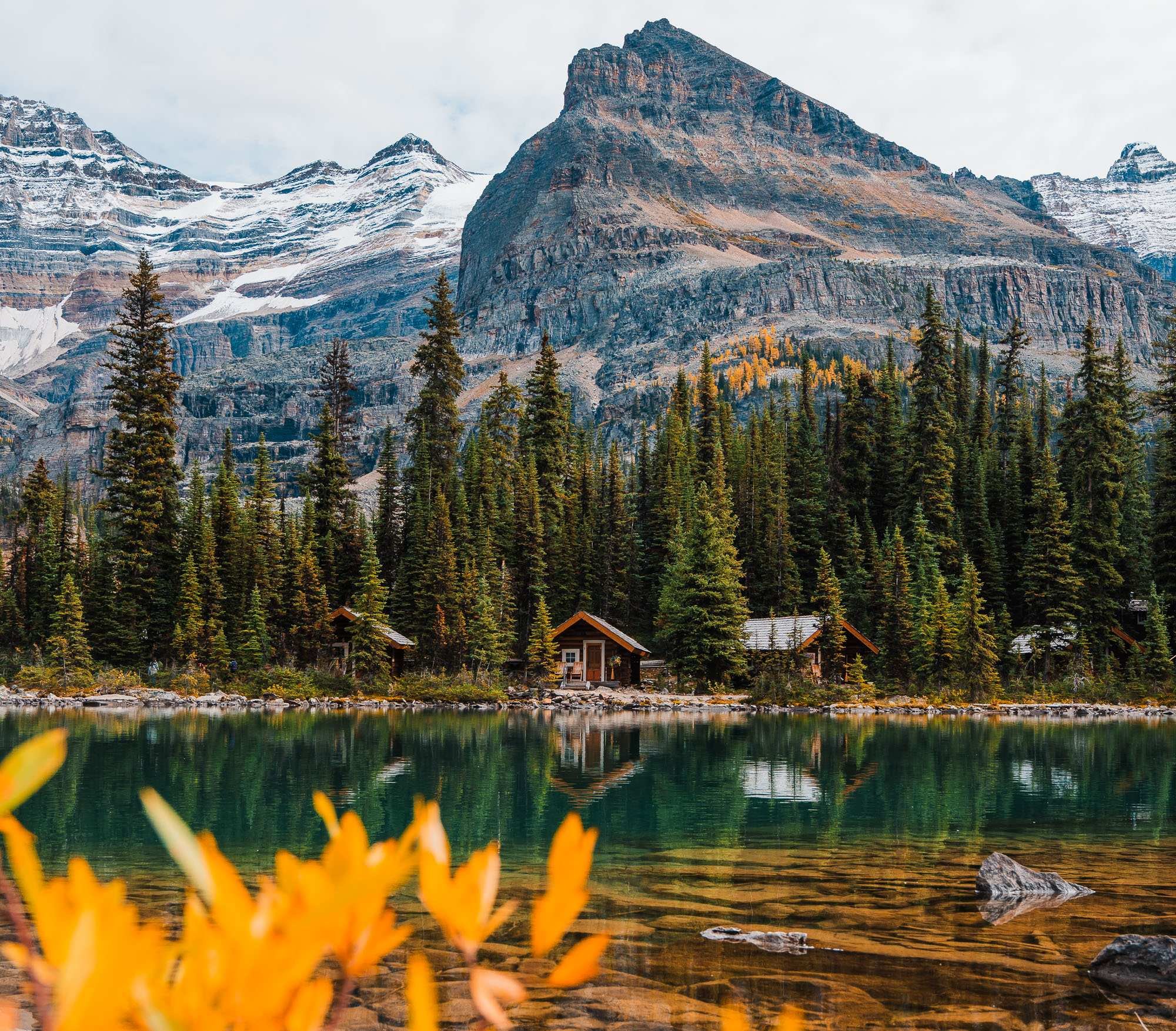 a few small cabins by a lake, with big mountains in the background