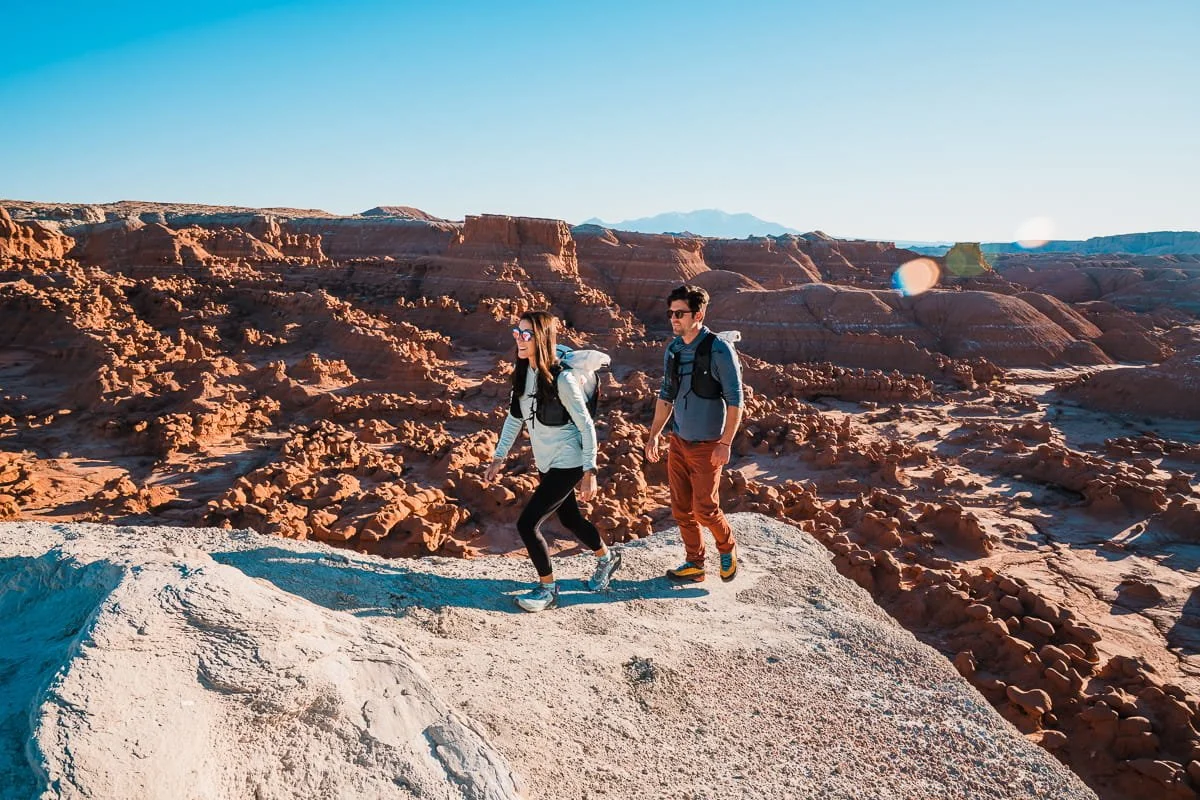 two hikers, hiking in the desert in goblin valley state park, utah