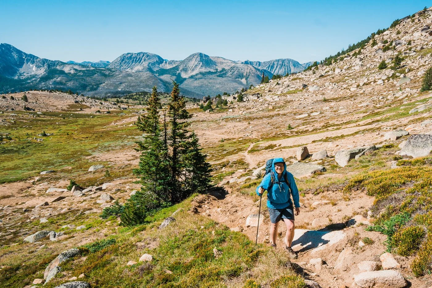 a man hiking up a trail to cathedral peak in the pasayten wilderness with the rocky trail and mountains stretching out behind him