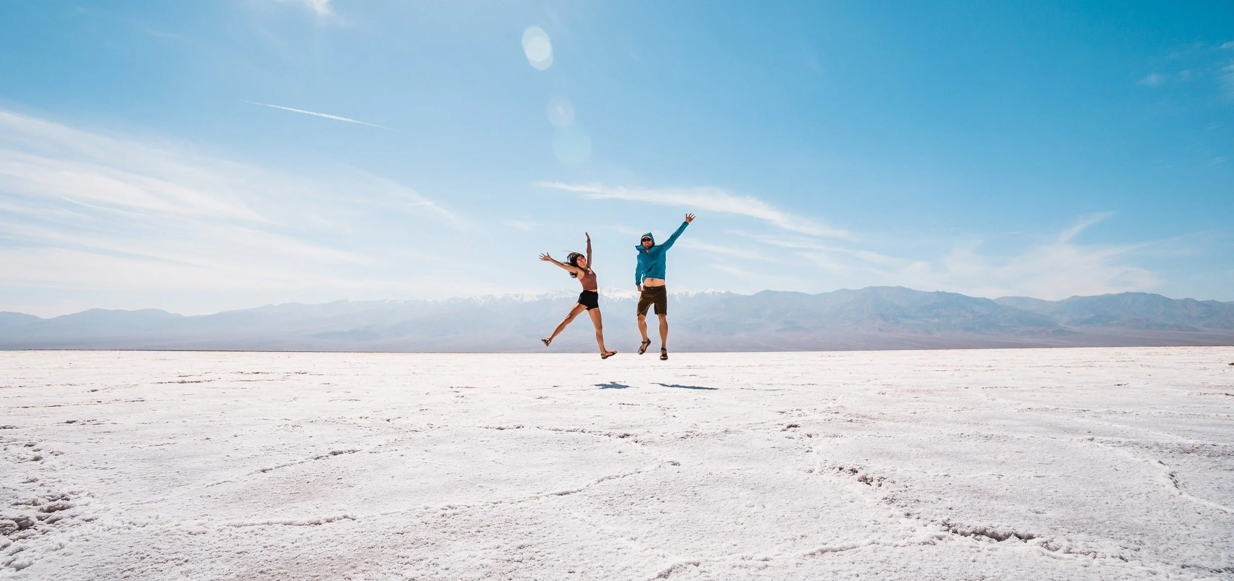 a couple jumping in the air on the white salt flats in death valley