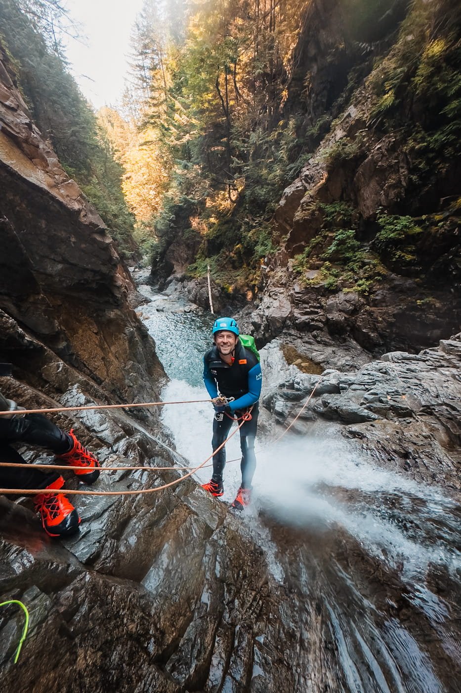 man looking up while rappelling through a waterfall on West Coast Canyoning adventure