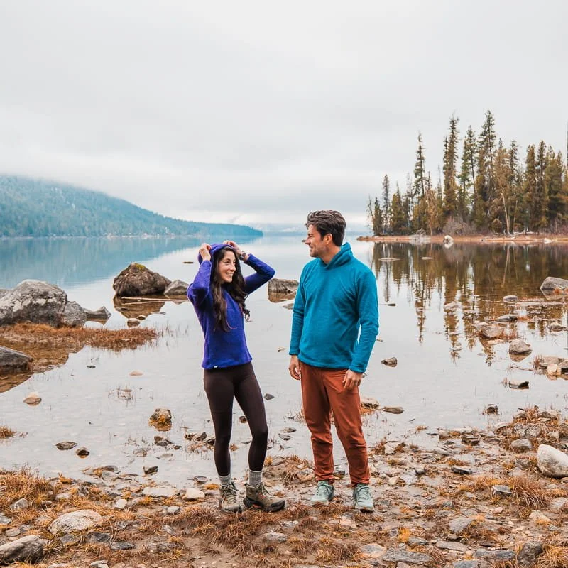 a couple standing in front of a lake in fleece alpha direct hoodies