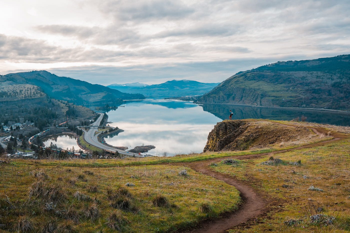 A tiny hiker standing on a cliff, overlooking the columbia river gorge in oregon