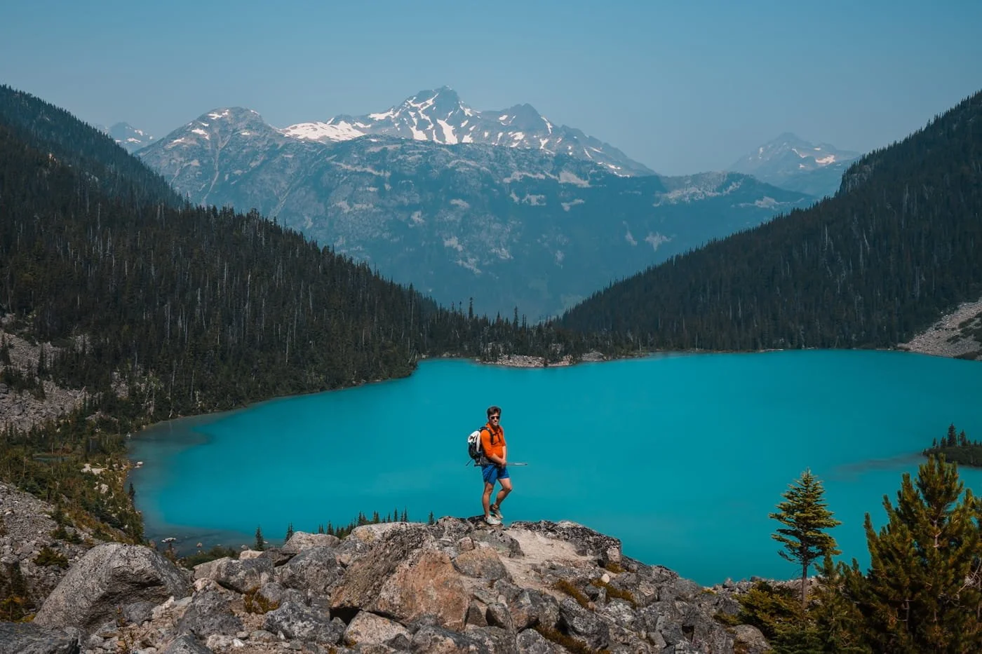 a hiker standing at a viewpoint overlooking upper joffre lake with mountains in the background