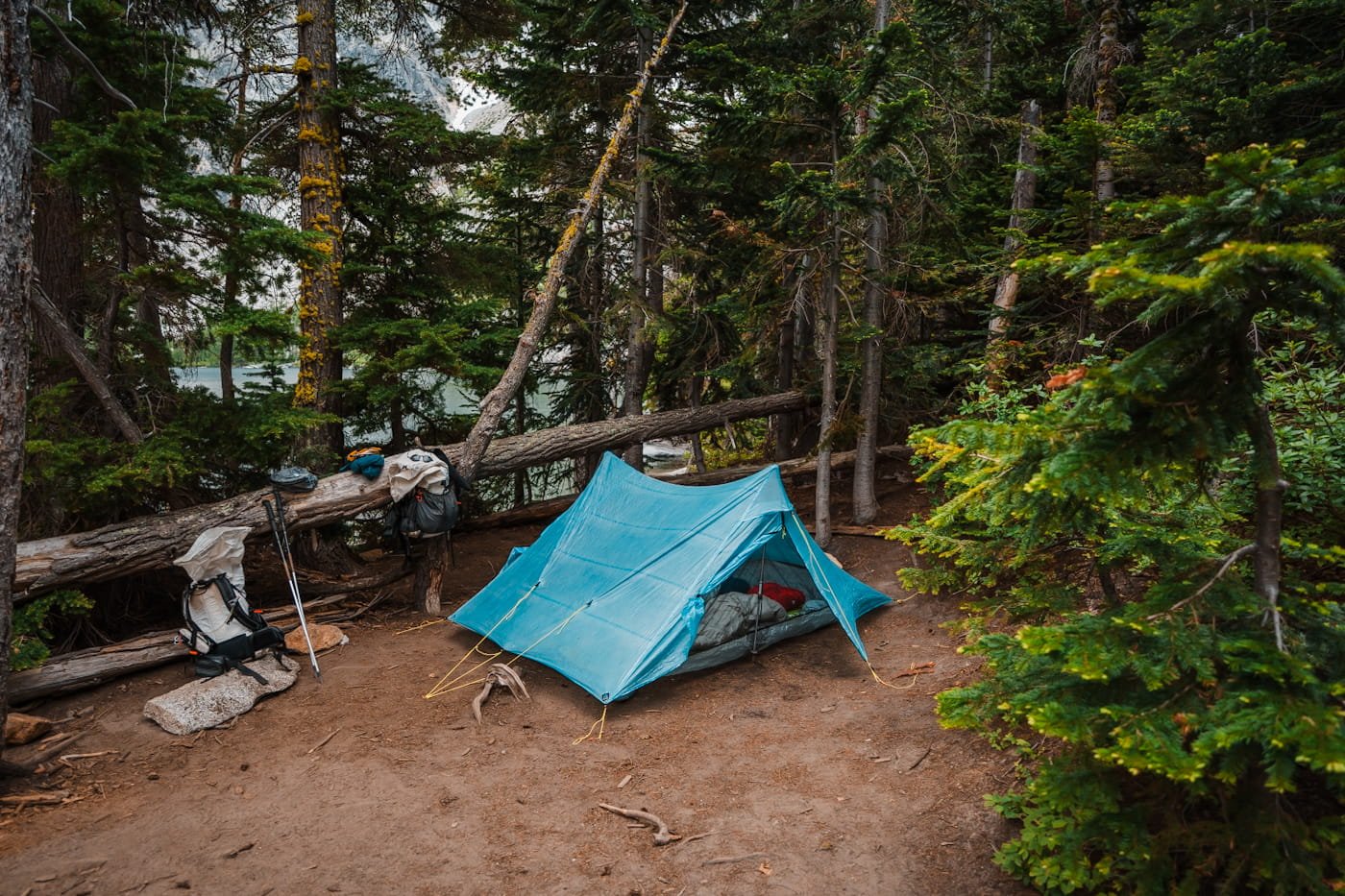 a blue trekking pole tent at a dirt campsite at colchuck lake
