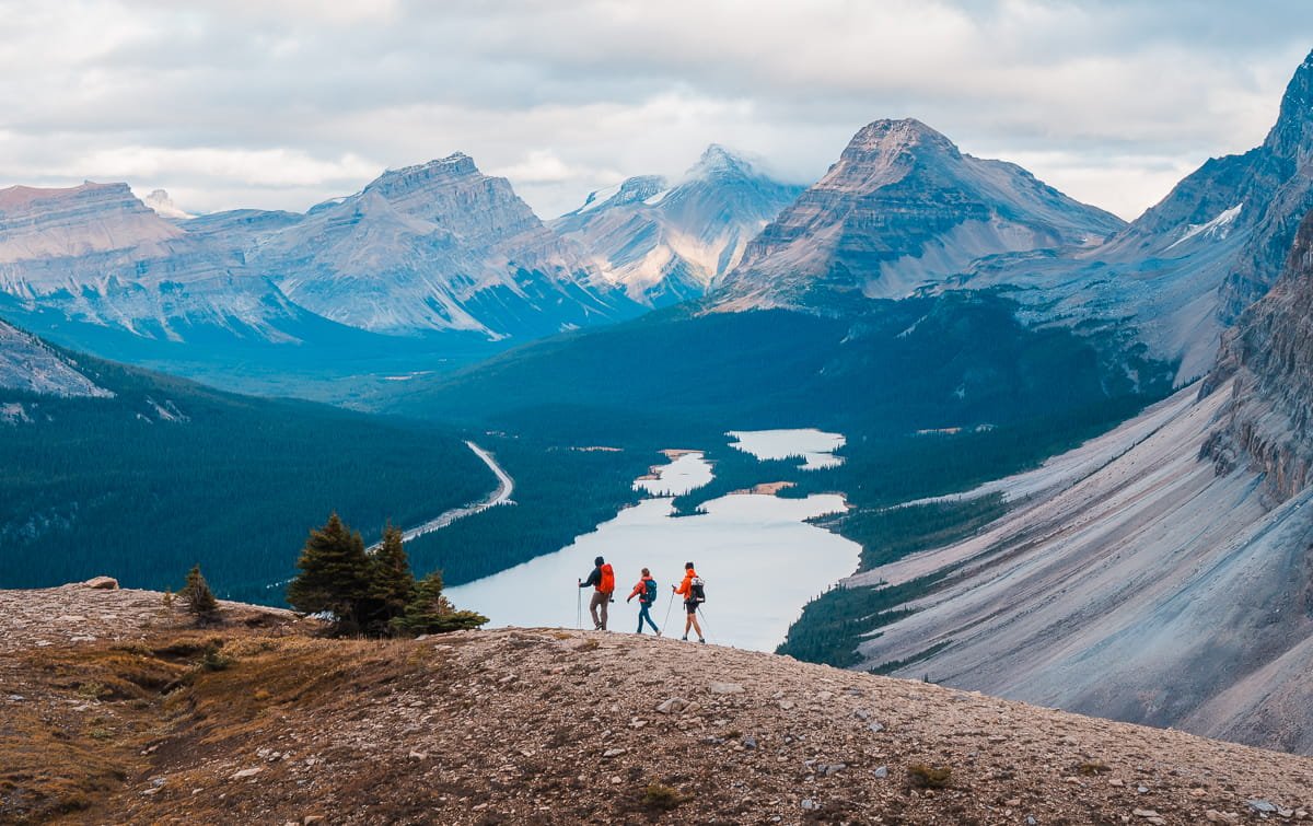 three hikers along a rocky ridge line above Bow Lake in the Canadian Rockies