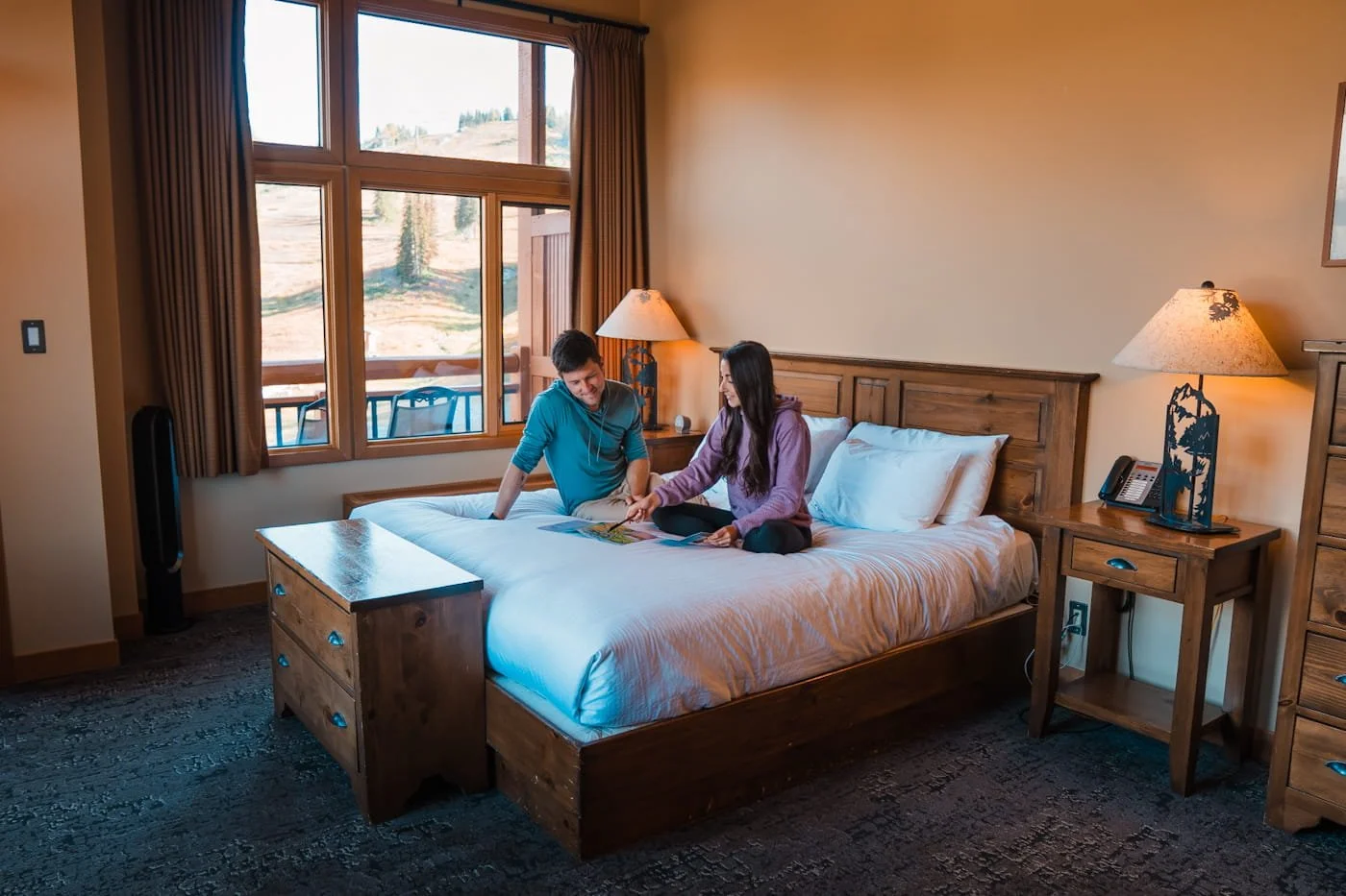 a couple sitting on a bed looking at a map in a room at the sunshine mountain lodge in banff alberta