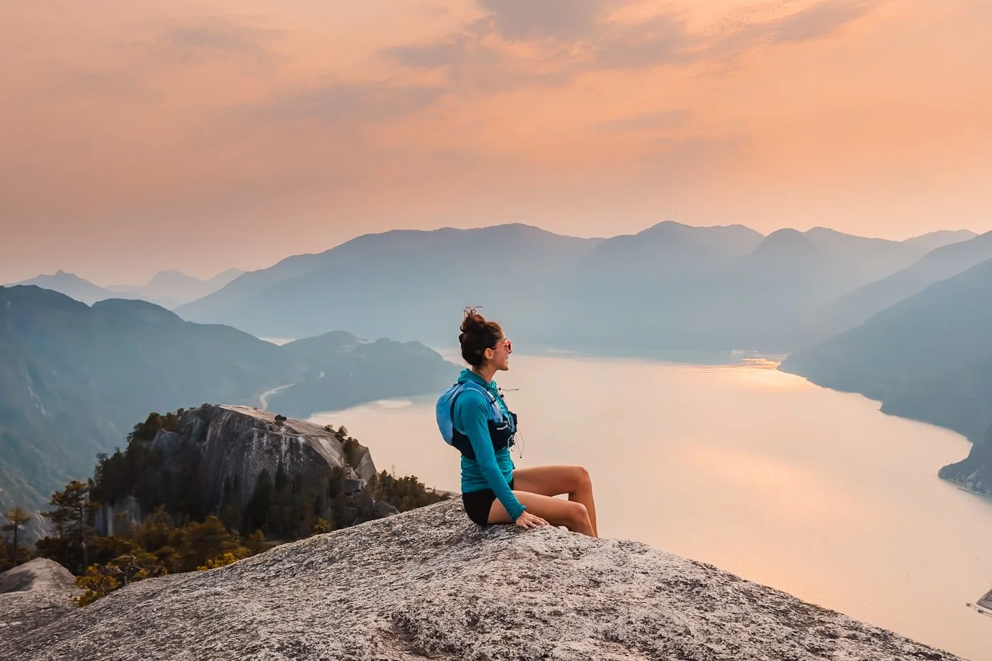 girl sitting on the second peak at sunset with views of first peak to her left